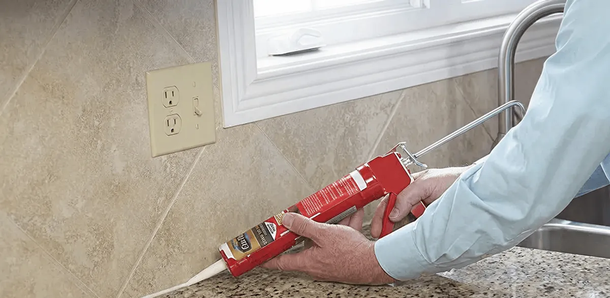 Handyman applying caulk along a kitchen backsplash and countertop seam in Green Bay, WI